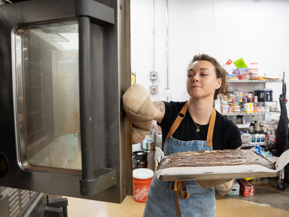 Ashley Orr, owner of Sweet Nothings Bakery and Cafe, pulls out gluten-free baked goods from the oven at Little Blue Bakehouse. Photo by Angelica Edwards.